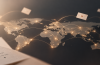 Ilustración de un mapa mundial con puntos luminosos conectados por cartas, que representa la plataforma Razones para quedarse, creada por un estudiante de la Universidad Atlántida.